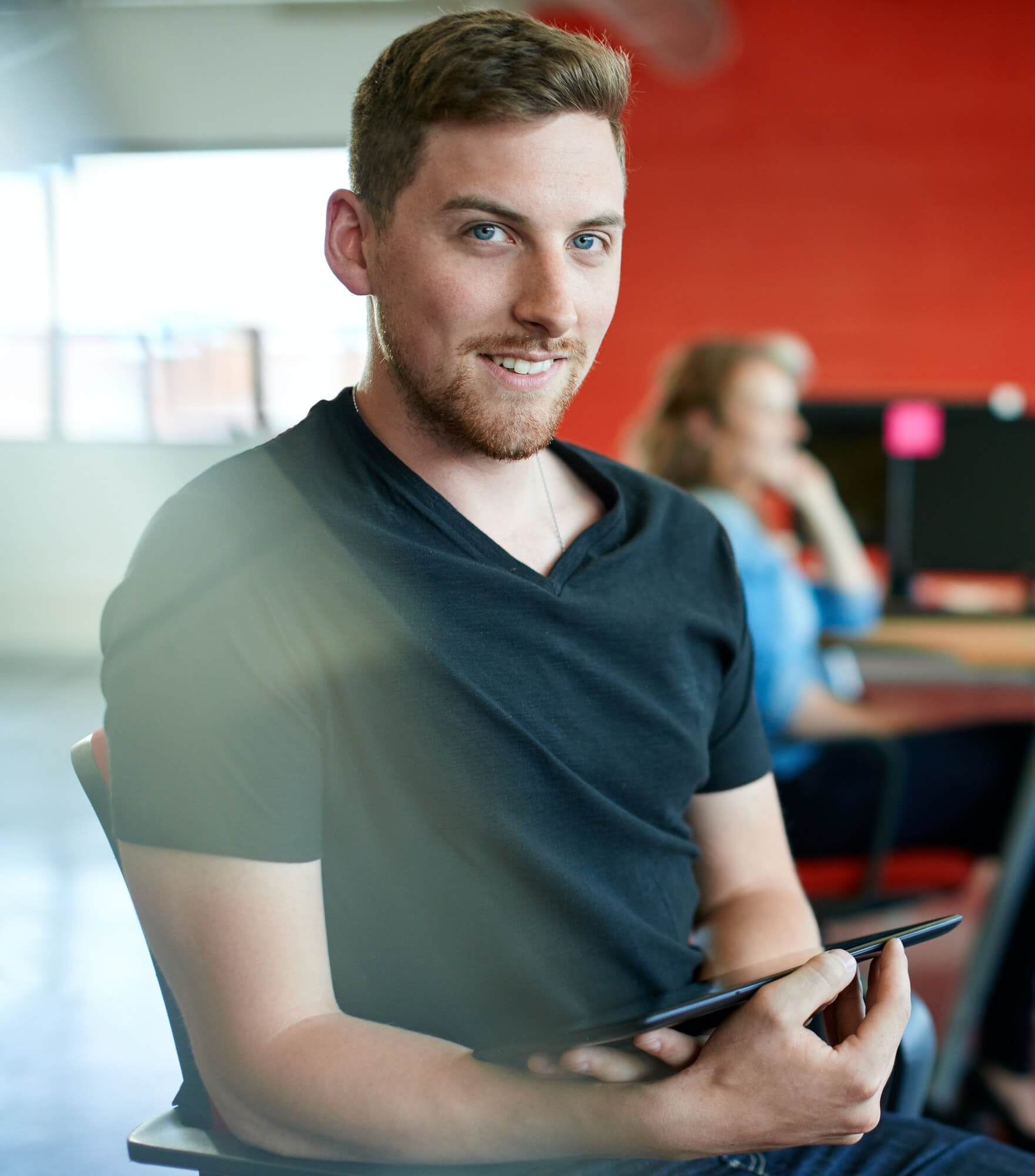 CONFIDENT MALE DESIGNER WORKING ON A DIGITAL TABLET IN RED CREATIVE OFFICE SPACE 3
